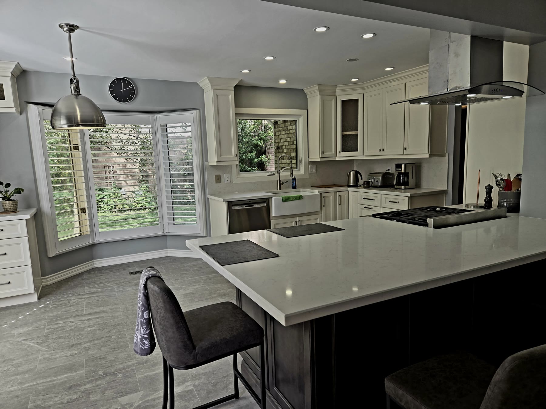 Finished custom kitchen with a large island, pale cabinetry, integrated lighting and stainless-steel appliances