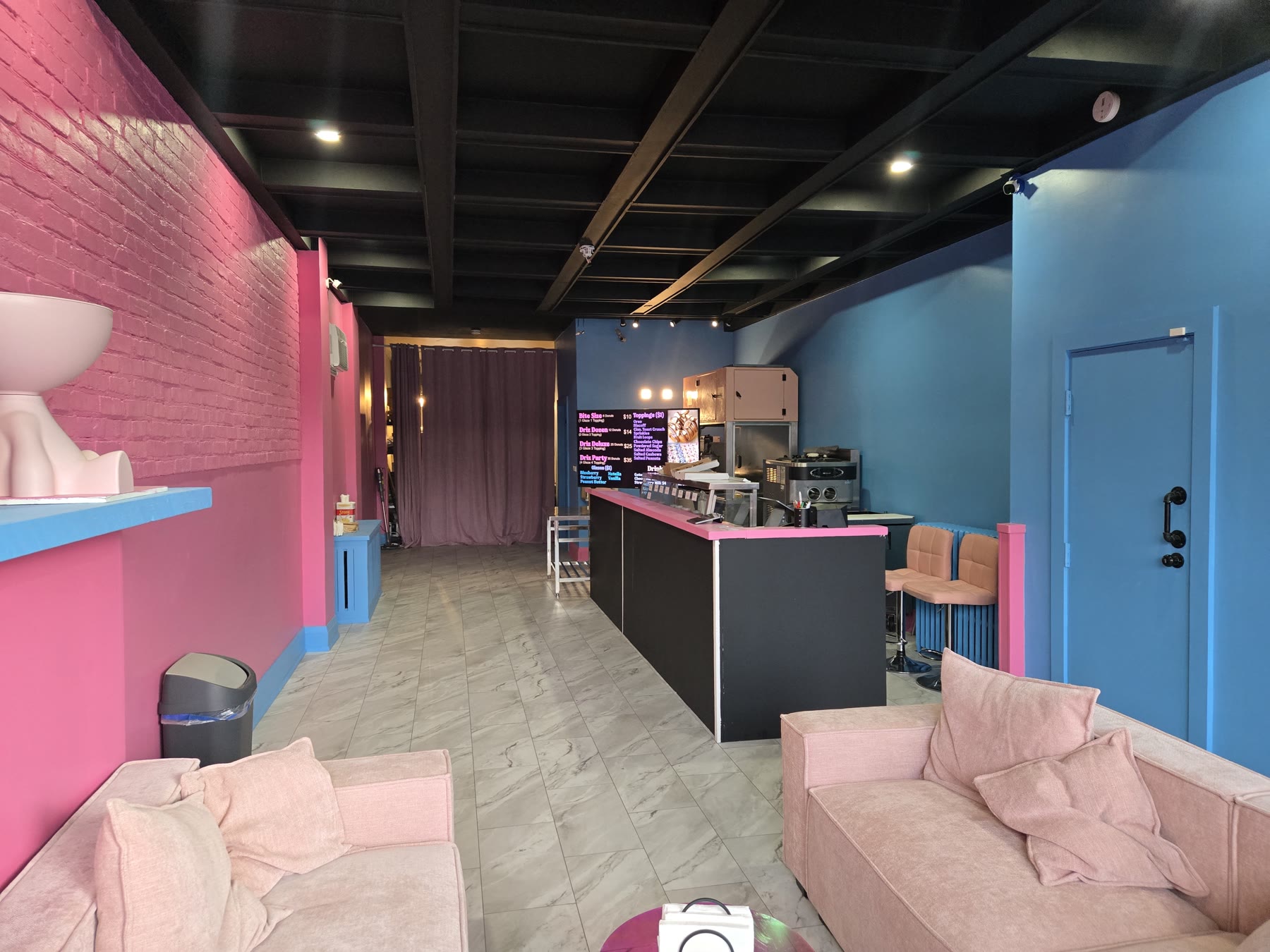 Finished commercial interior with bright blue walls, pink accents, service counter and seating