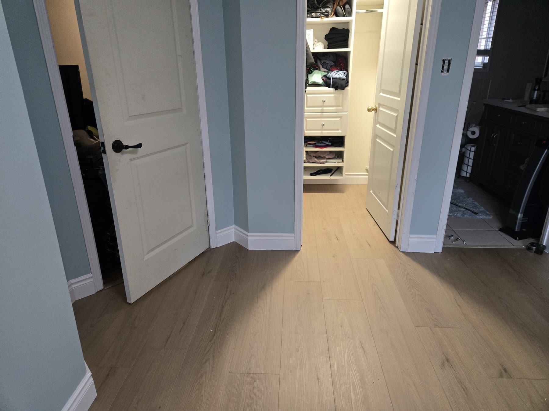 Connected interior spaces with continuous flooring, baseboards and dark hardware