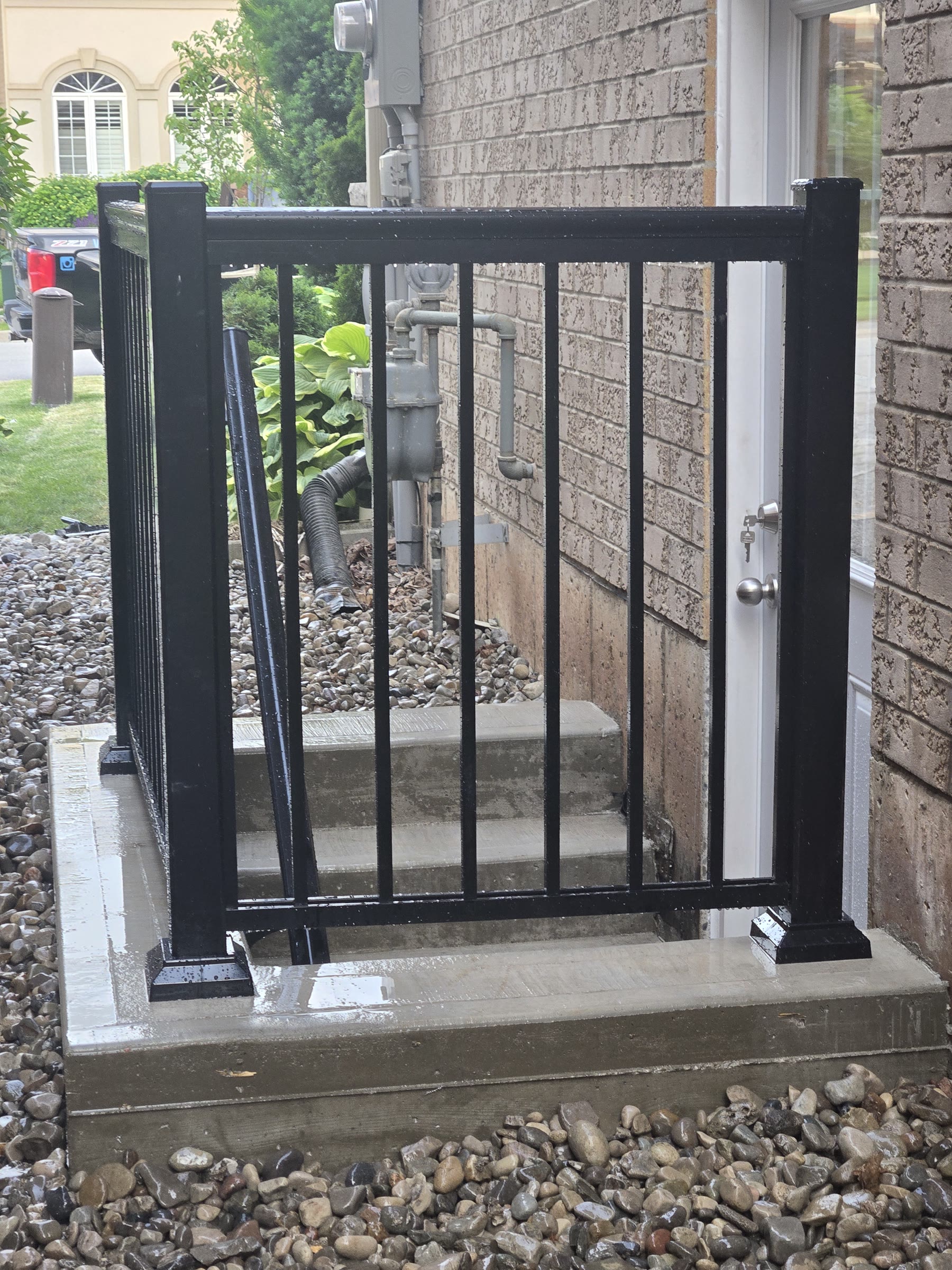 Black guardrail and gate protecting the basement side entrance